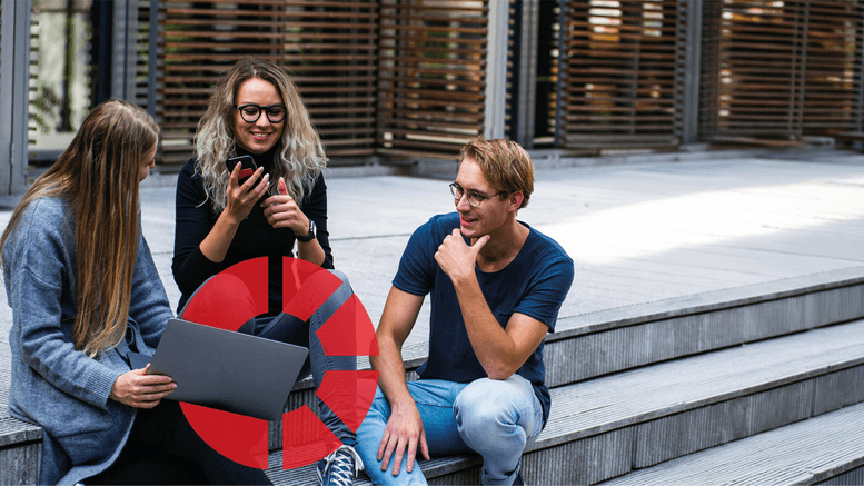 Three students sat together on steps with a laptop and mobile phone