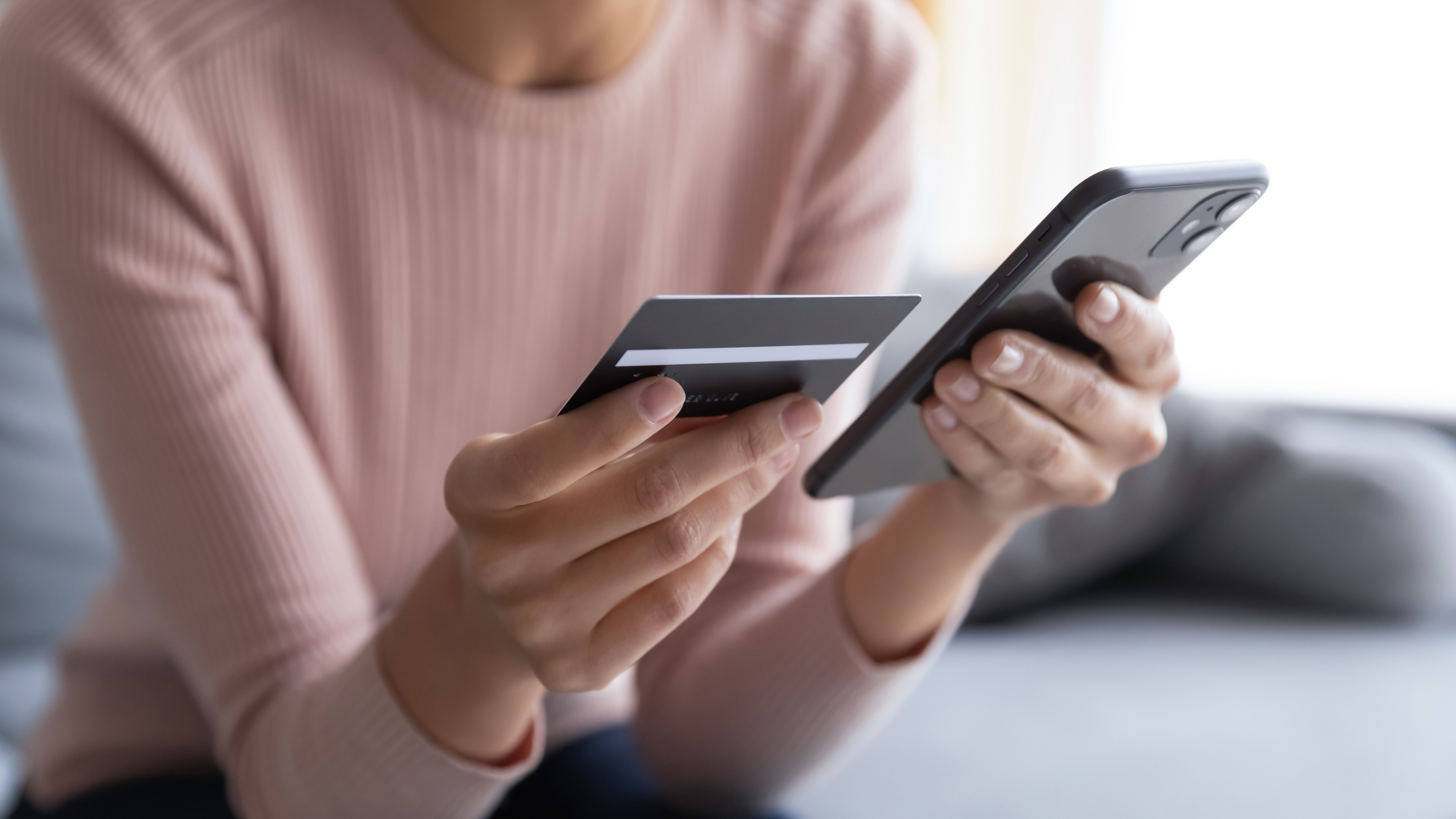 Woman checking online bank account using a mobile and holding a credit card.