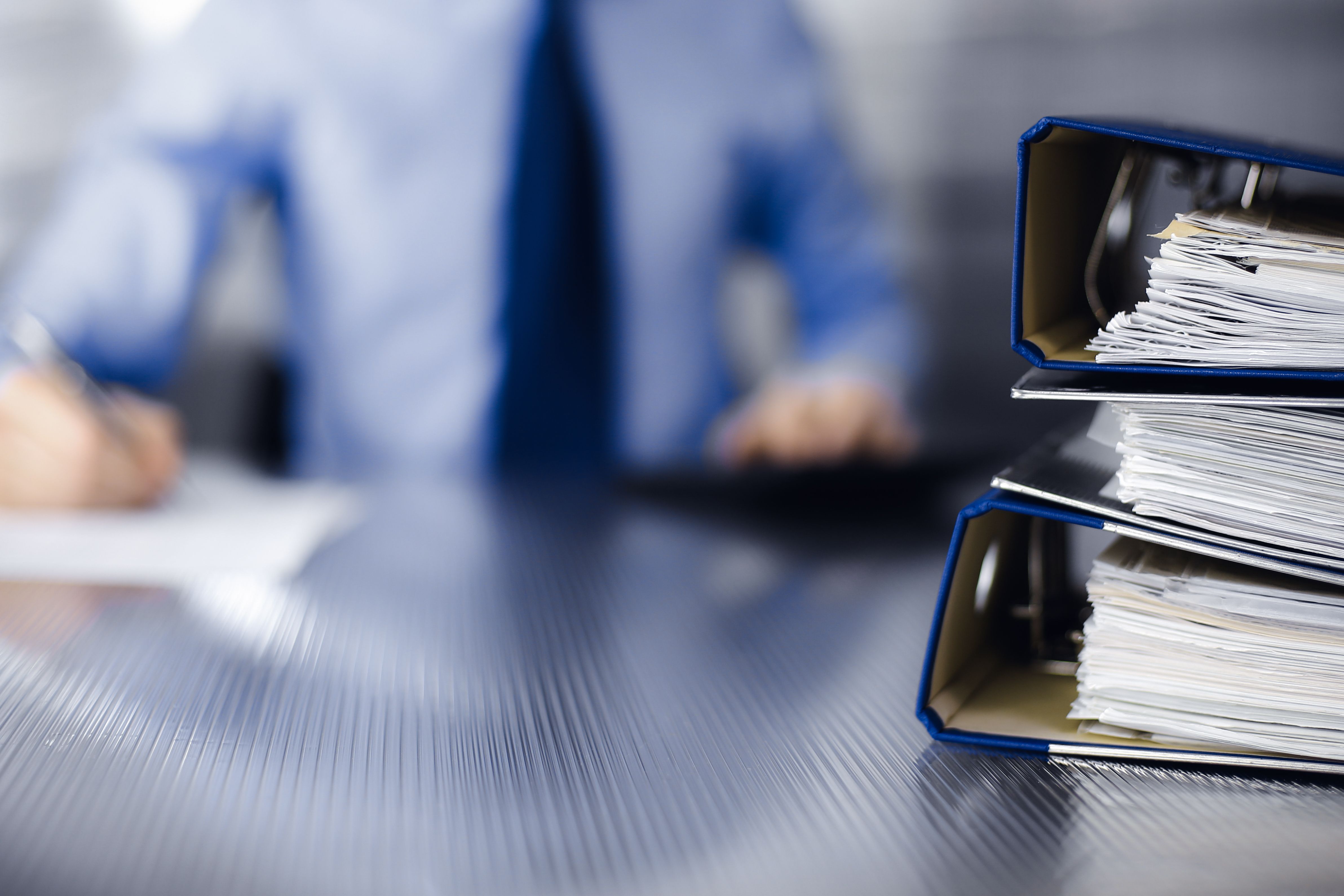 Man behind a desk with binders stacked on top of each other